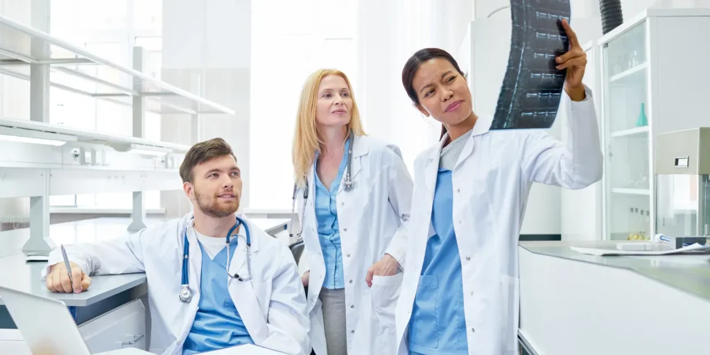 Group of radiologists collaborating and reviewing scans in a hospital setting.