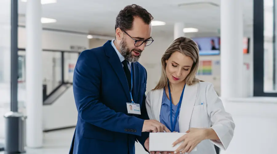 Male and female medical professionals reviewing a clipboard in a hospital setting