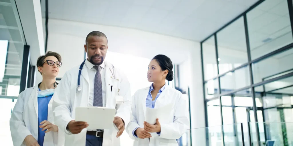 Group of medical professionals discussing patient records in a hospital corridor — Reliable Hepatologist Email List