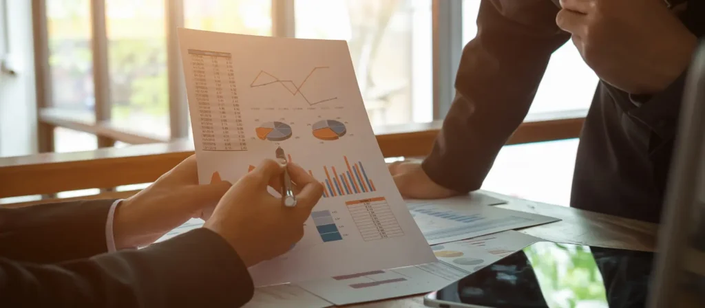 Business professionals analyzing pricing charts and data reports on a digital tablet.
