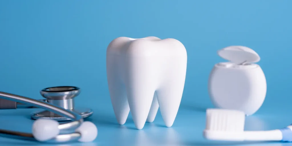 Dental equipment including tooth model, mirror, and tools arranged on blue background - representing effective strategies for utilizing dental hygienist email lists for targeted B2B healthcare marketing and professional communication campaigns