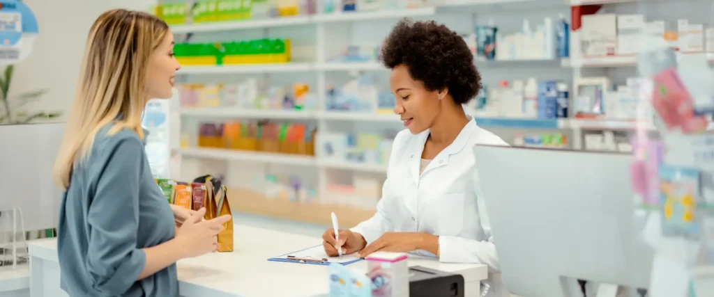 Pharmacist consulting a customer at the counter in a modern pharmacy